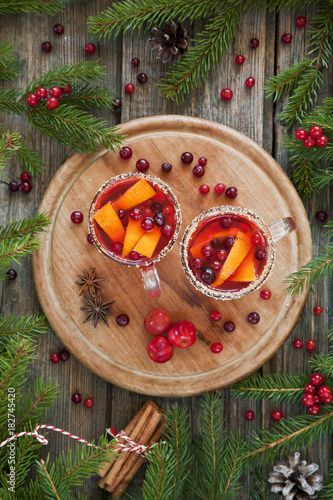 Cup of hot spicy drinc on a tray with branches of coniferous tree. Rustic wooden background, top view, close-up, Christmas concept photo