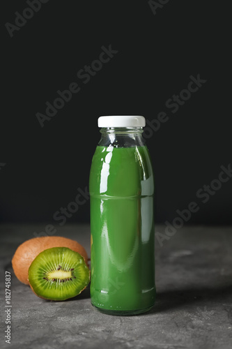 Bottle of kiwi juice on table against black background