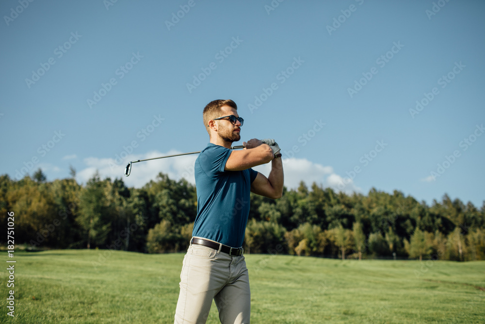 Full length view of man in cap holding golf club and hitting ball on green lawn Full length view of man in cap holding golf club and hitting ball on green lawn