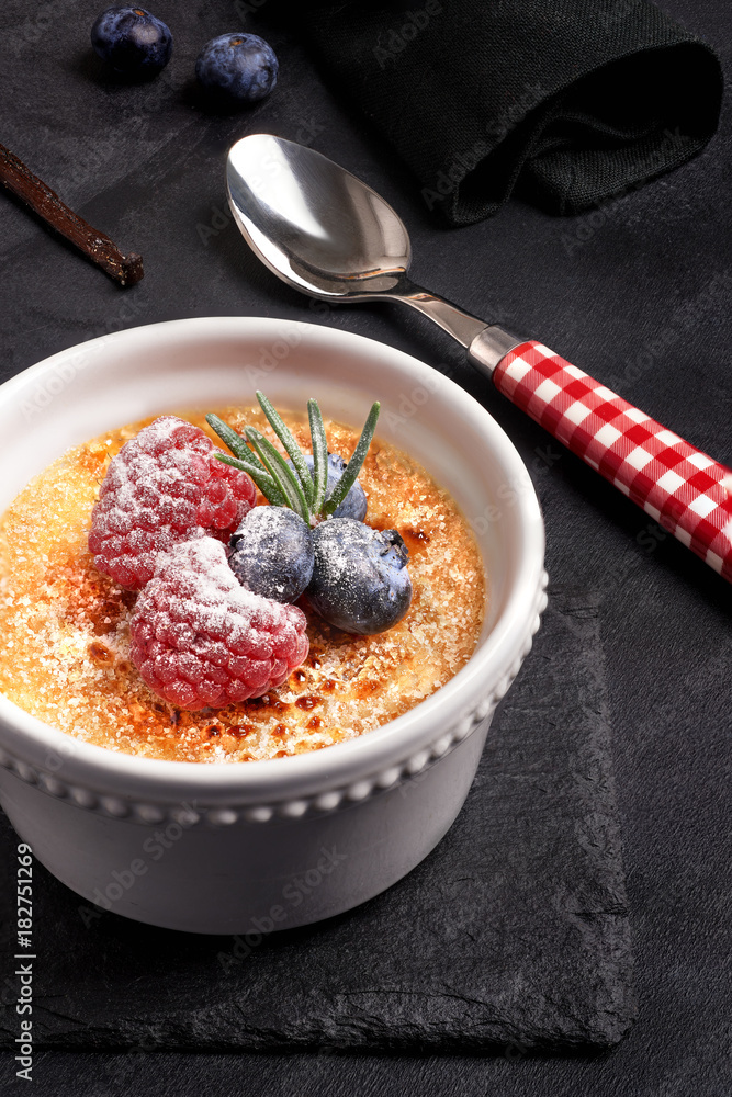 Creme brulee with berries on dark stone Creme brulee with berries on dark stone