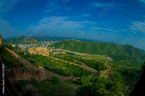 Beautiful landscape of Amber Fort with green trees  mountains and small houses near Jaipur in Rajasthan  India. Amber Fort is the main tourist attraction in the Jaipur area