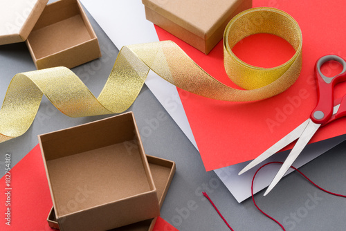 Empty brown gift boxes and gold ribbon on gray background. Gift wrapping. Preparing ornaments.