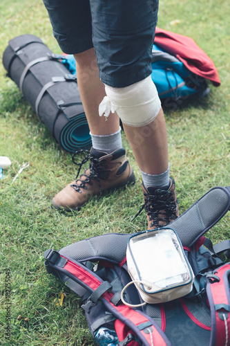 Woman dressing the wound on her knee on hike