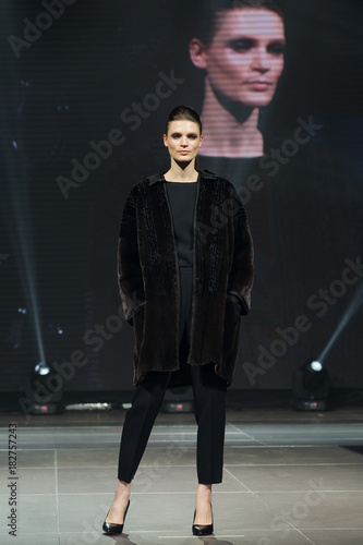 Vászonkép Beautiful fashion model  walks on runway in fur coat with online screen on backg