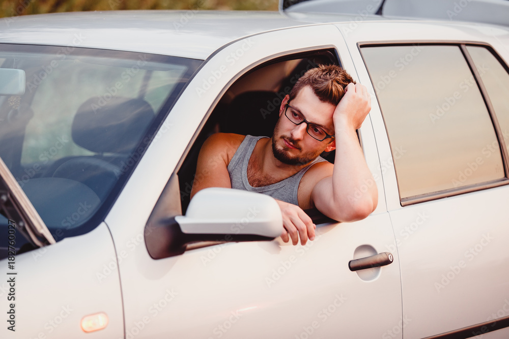 A young man waits for assistance in his car A young man waits for assistance in his car