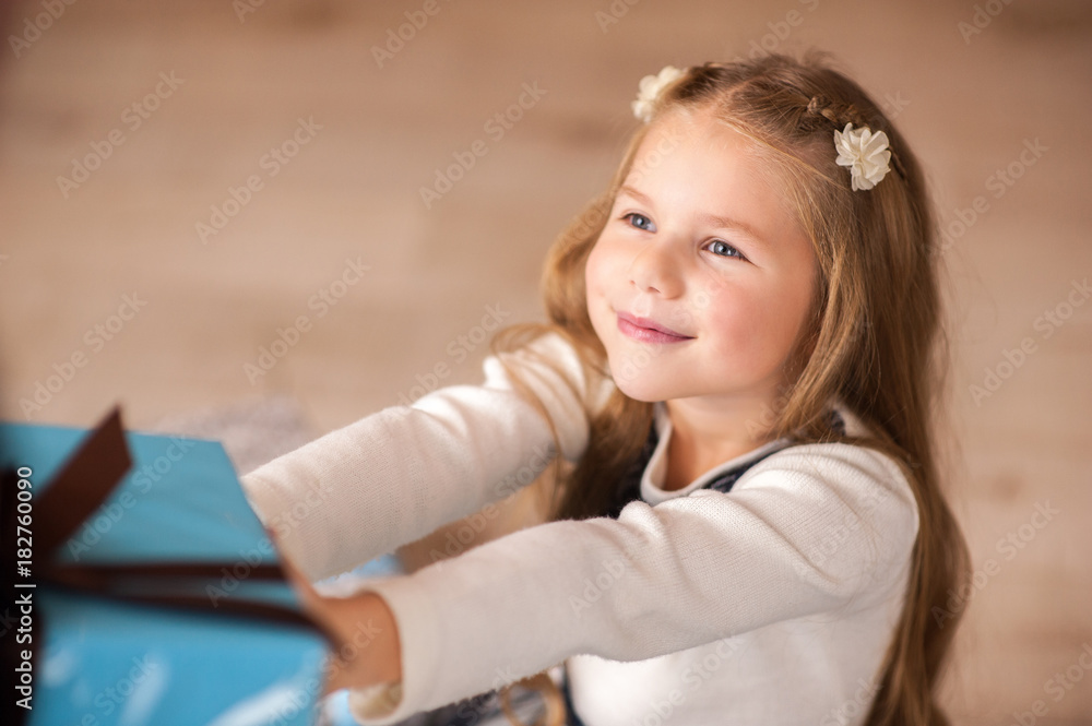 Girl, daughter, smiling, glad opens and .receives gifts on Christmas Eve or New Year near Christmas tree