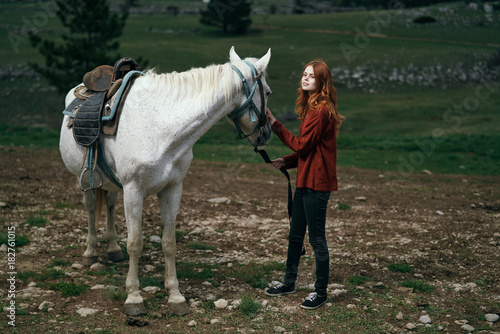 a girl in red leads a white horse