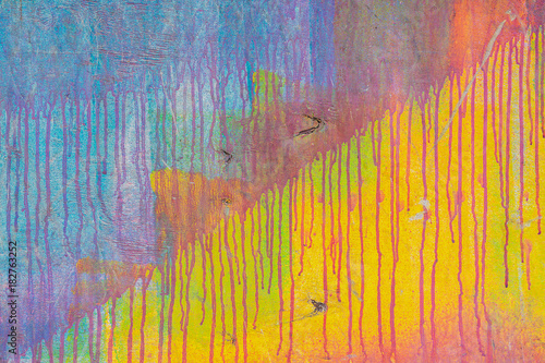 Close-up of abstract dirty painted wooden surface, flowing paint of different bright colors, as graffiti. Colorful grunge texture of wall. Abstract modern background