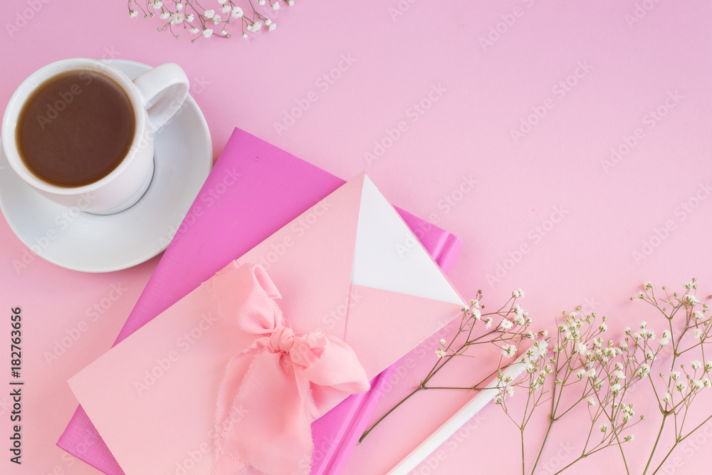 Table of a business woman with a pink notebook on a pink background with a white pen
