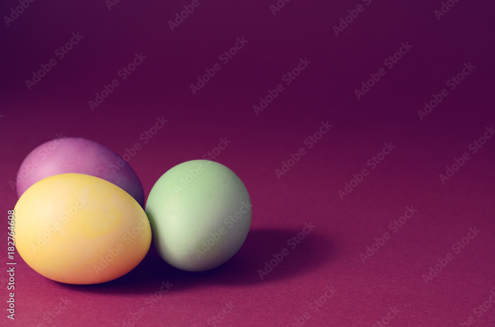 Trendy photo of Three multi colored easter eggs on a dark purple background. Trendy photo of Three multi colored easter eggs on a dark purple background.