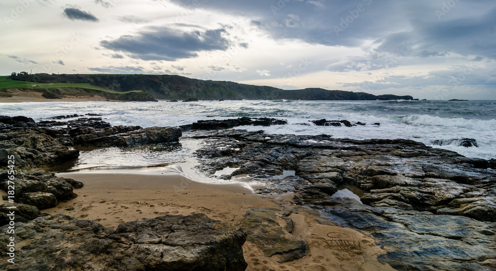 Waves on the coast in Verdicio beach in Asturias, Spain.Choppy sea in a virgin beach with rocks and foam at evening