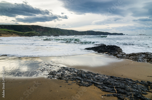 Waves on the coast in Verdicio beach in Asturias  Spain.Choppy sea in a virgin beach with rocks and foam at evening