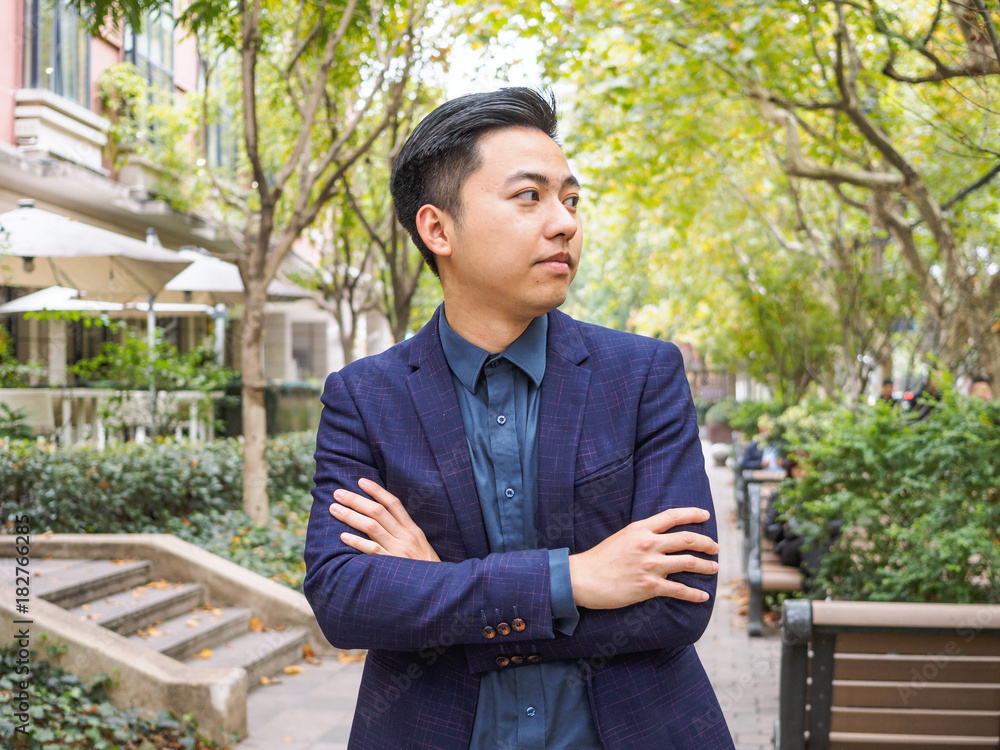 Portrait of a handsome Chinese young man in blue suit looking aside with arms crossed. Portrait of a handsome Chinese young man in blue suit looking aside with arms crossed.