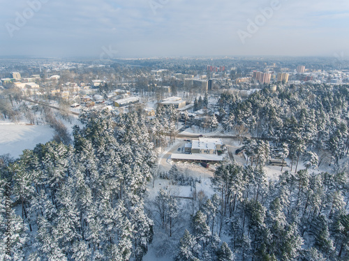 Aerial view over snowy pine tree forest revealing Druskininkai city, Lithuania. photo