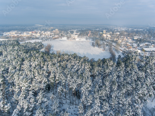 Aerial view over snowy pine tree forest revealing Druskininkai city, Lithuania. photo