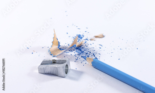 Blue pencil with sharpening shavings on white background