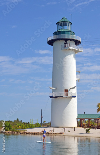 Faux lighthouse tower used as a zip line station and a woman on a paddle board in a lagoon on an island leased by a cruise line off the coast of Belize