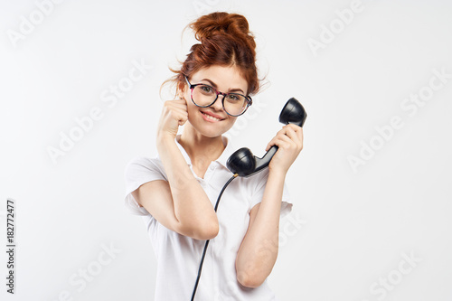 Joyful red-haired girl with a telephone receiver on a light background