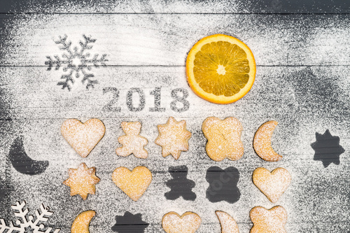 2018 numbers and christmas different shaped cookies with sugar powder and orange slice on wooden table