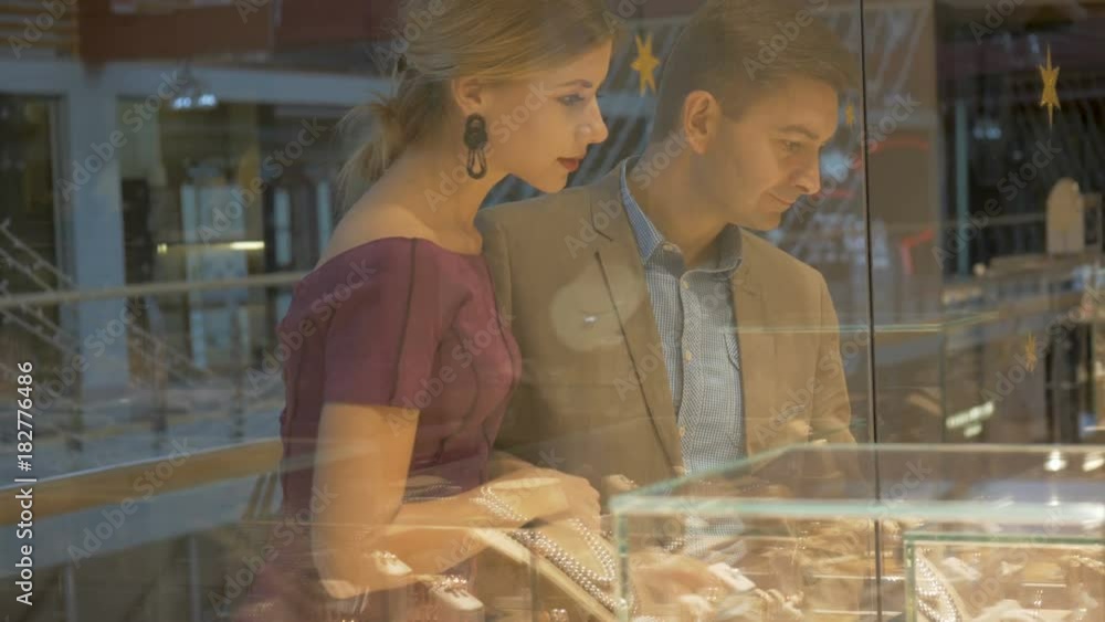 A jewelry store. A young couple is looking at jewelry.