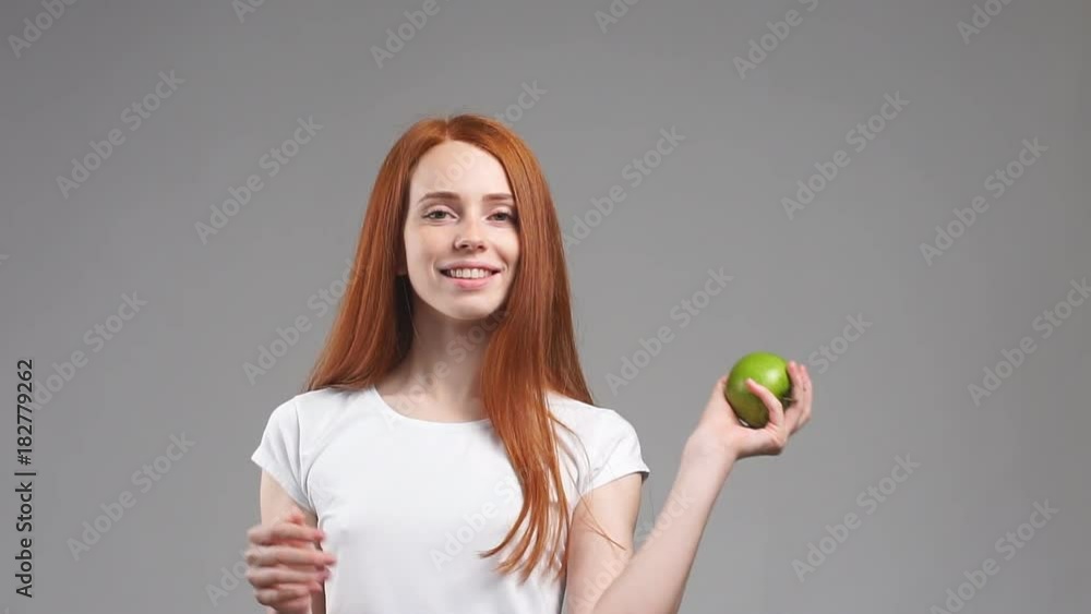 Portrait of young redhead girl holds up a green apple. Slow Motion. Portrait of young redhead girl holds up a green apple. Slow Motion.