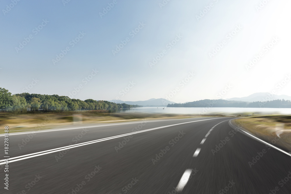 Naklejka premium empty asphalt road with beautiful lake