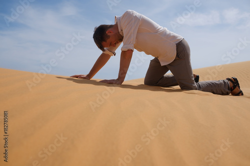 Man walking alone in the sunny desert. He is lost and out of breath. No water and energy.