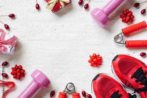 Flat lay of Merry Christmas and Happy new year and any holidy present boxes for healthy and active lifestyle concepts. Composition with dumbbells, sport shoes and red gift boxes with bow on wood  photo