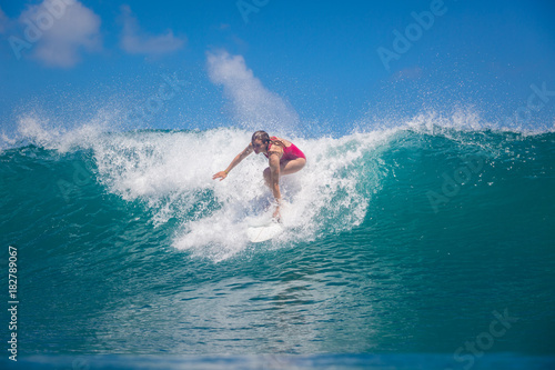 Indonesia, Bali, July 23 2016: A female surfer, Leonor Fragoso riding big blue ocean surfing wave, shot from water level © willyam