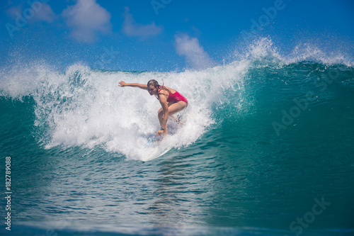 Indonesia, Bali, July 23 2016: A female surfer, Leonor Fragoso riding big blue ocean surfing wave, shot from water level