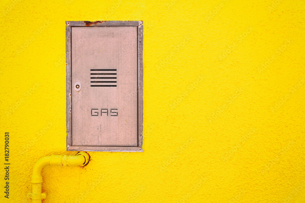 Gas pipe and a manhole in a bright yellow wall Gas pipe and a manhole in a bright yellow wall