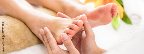 Professional therapist giving reflexology Thai foot massage to a woman in spa