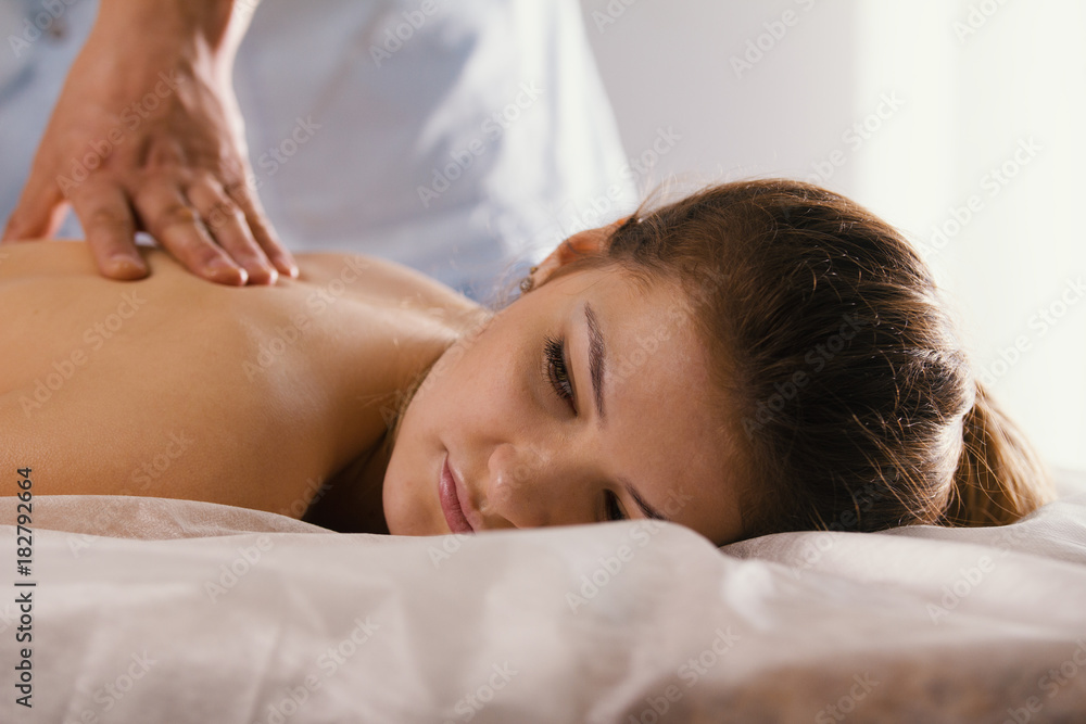 Blonde young woman model receiving relaxing massage in spa room Blonde young woman model receiving relaxing massage in spa room