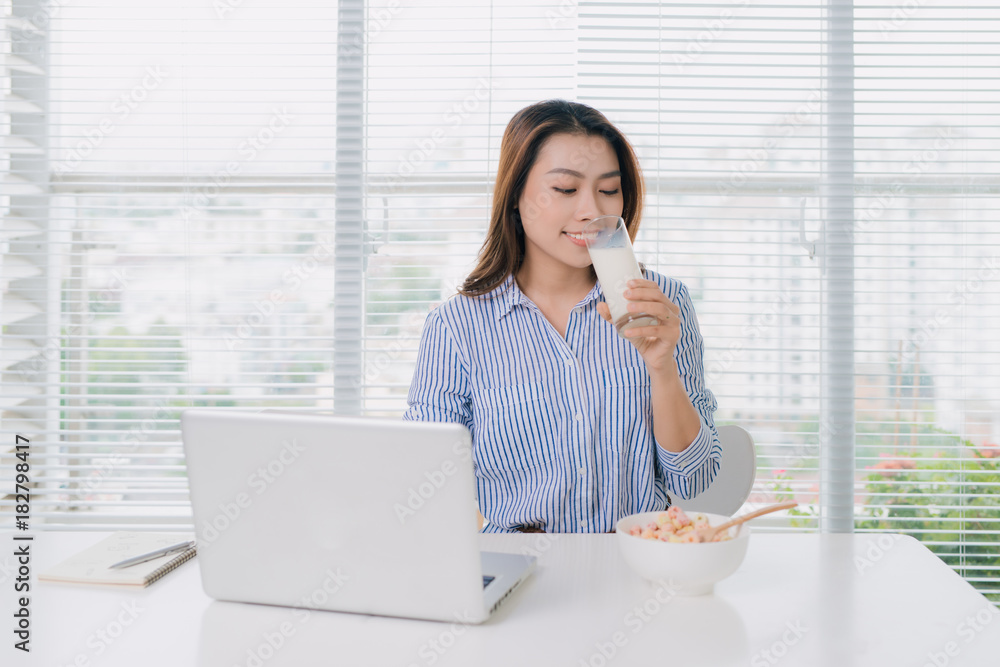 Healthy asian woman drinking a glass of milk at desk in office