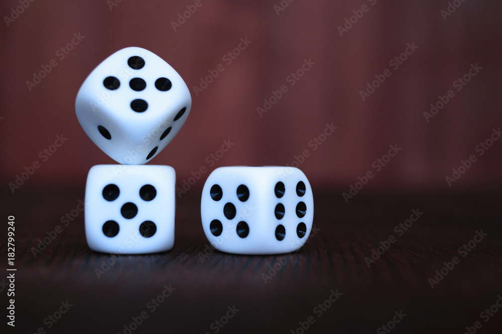 Heap of three white plastic dices on brown wooden board background. Six sides cube with black dots. Numbers 1, 3, 5, 6. Heap of three white plastic dices on brown wooden board background. Six sides cube with black dots. Numbers 1, 3, 5, 6.