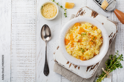 Pumpkin risotto with thyme, garlic, parmesan cheese and white wine on light wooden background. Selective focus. Rustic style. Top view.