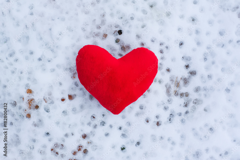 Red plush heart on snow.