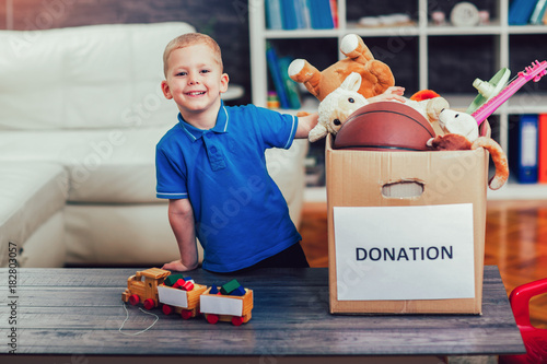 Foto Boy taking donation box full with stuff for donate