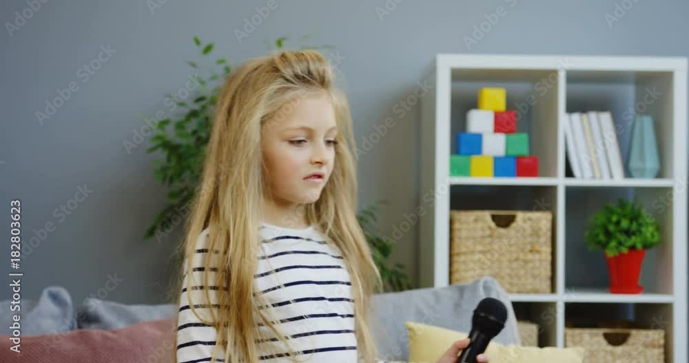 Little lovely blonde girl with long hair dancing and singing in the mic in the nice living room at home. Indoor Little lovely blonde girl with long hair dancing and singing in the mic in the nice living room at home. Indoor