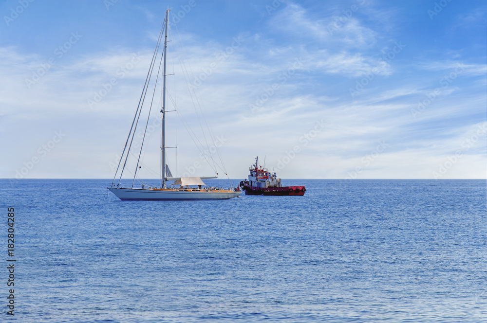 Two docked boat on the horizon of blue peaceful sea with cloudy sky