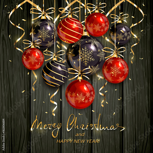 Red and black Christmas balls and golden streamers on black wooden background