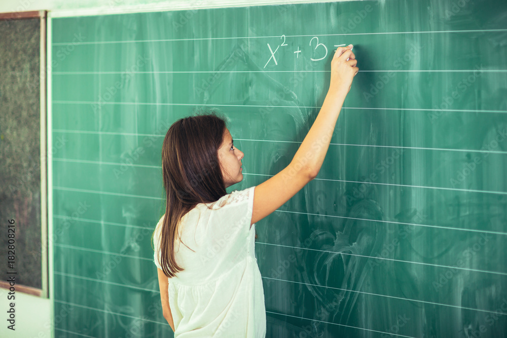 Happy schoolchild writing on blackboard with chalk Happy schoolchild writing on blackboard with chalk
