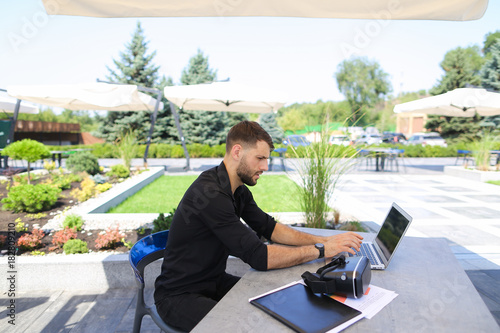 Photos Happy businessman works outside with laptop and enjoying with vi