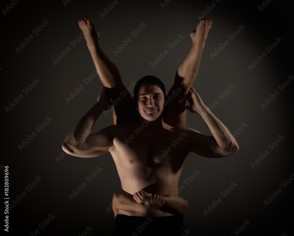 Young sports couple doing acroyoga exercises in a dark room Young sports couple doing acroyoga exercises in a dark room