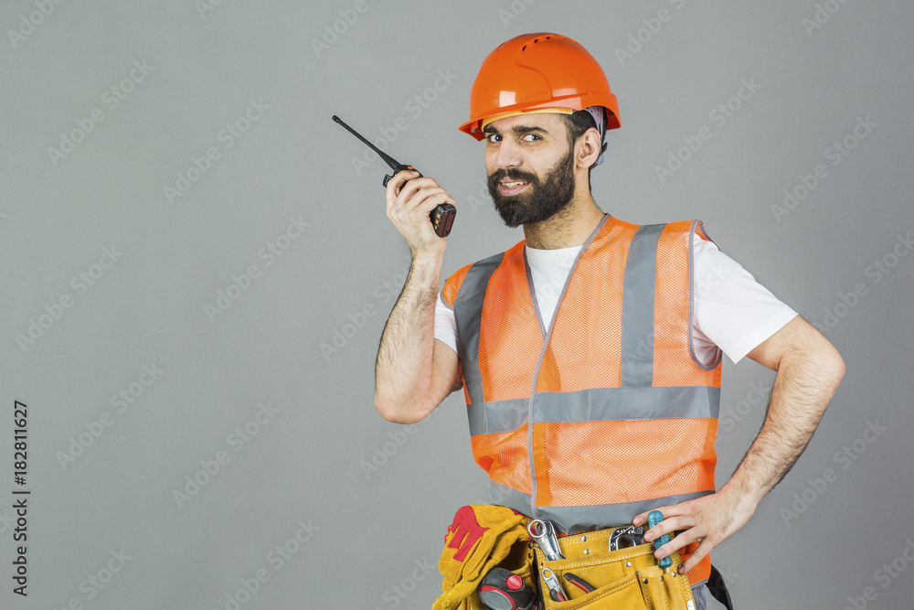 A Syrian man-builder with a walkie-talkie in his hands. On a gray background A Syrian man-builder with a walkie-talkie in his hands. On a gray background
