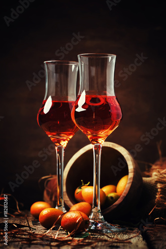 Kumquat liqueur, vintage wooden background, selective focus