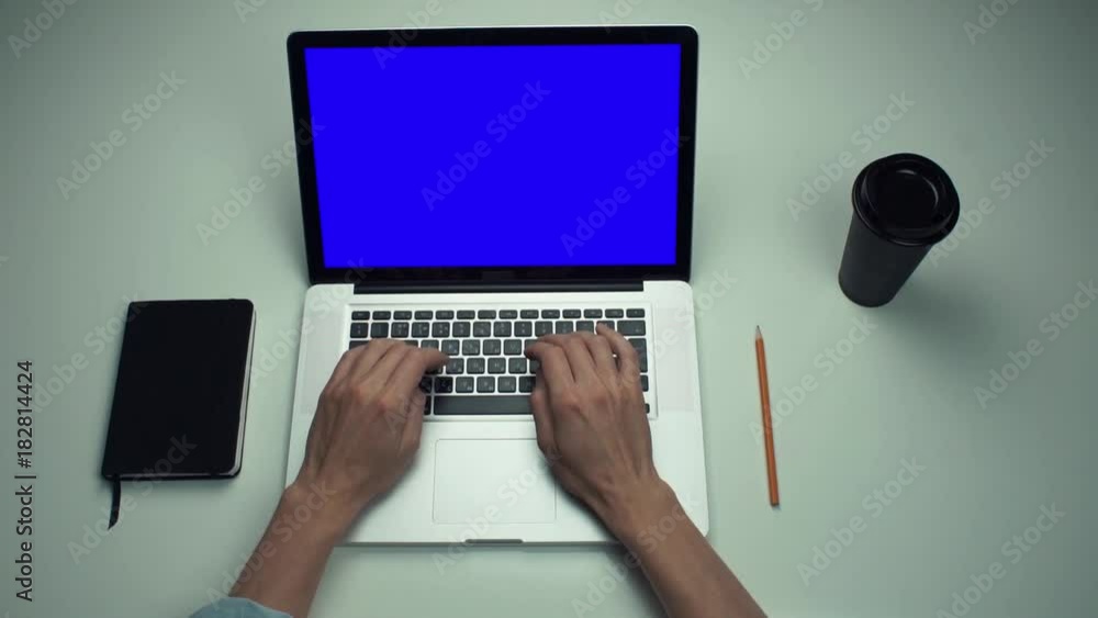 Top view male hands using laptop computer with green screen at white desk Top view male hands using laptop computer with green screen at white desk