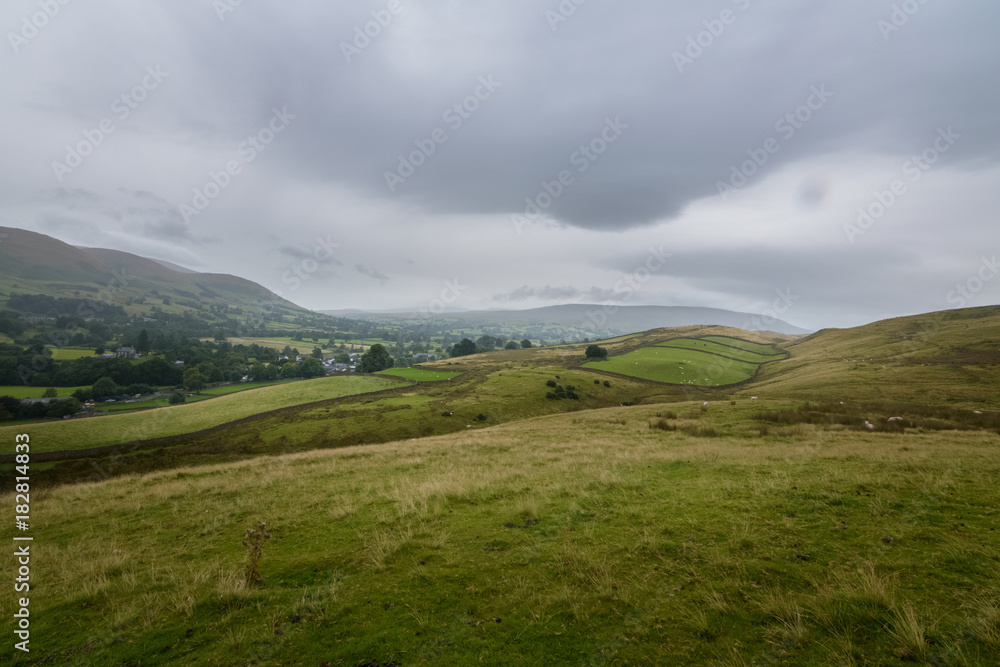 Green farmland on the hills above Sedbergh town, England Green farmland on the hills above Sedbergh town, England