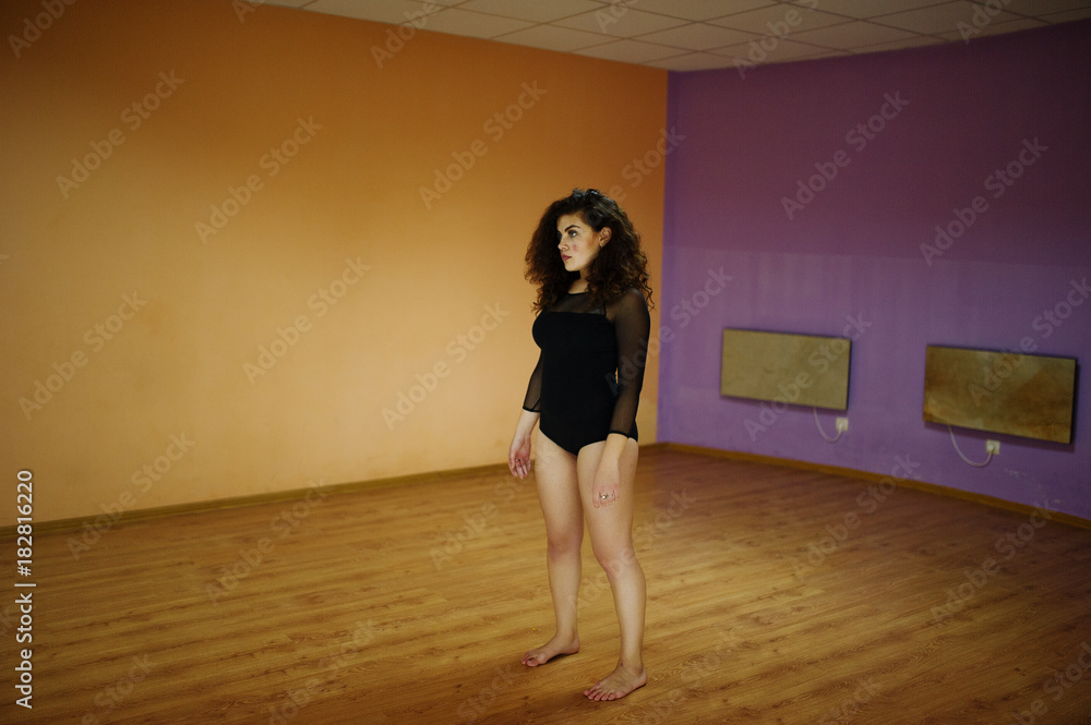 Curly brunette plus size model doing acrobatic at dance room.