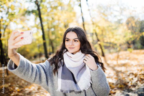 Young girl takes a selfie on the backgroung autumn park photo